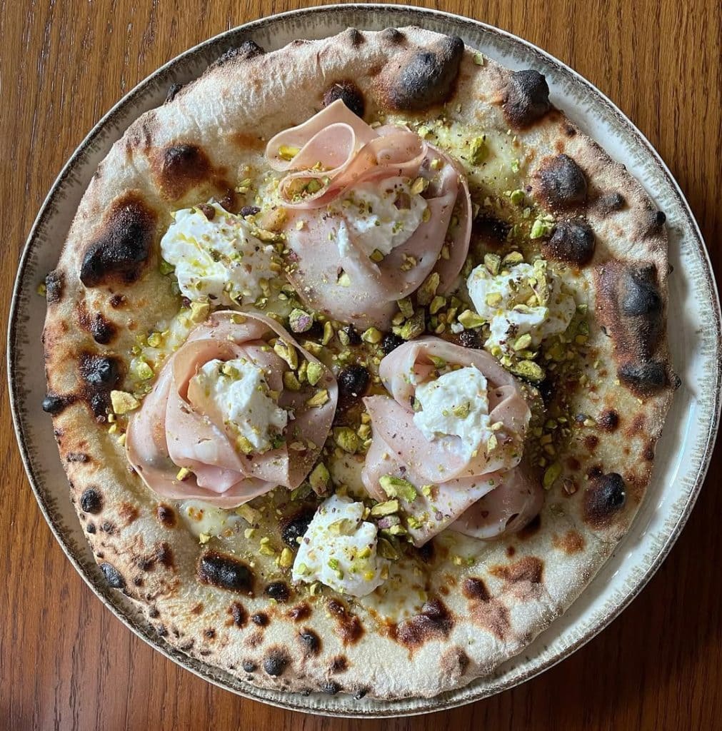 Homemade pizza with mortadella, ricotta, and pistachio. Baked in an Ooni outdoor pizza oven.