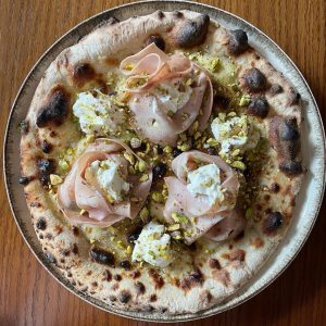 Homemade pizza with mortadella, ricotta, and pistachio. Baked in an Ooni outdoor pizza oven.