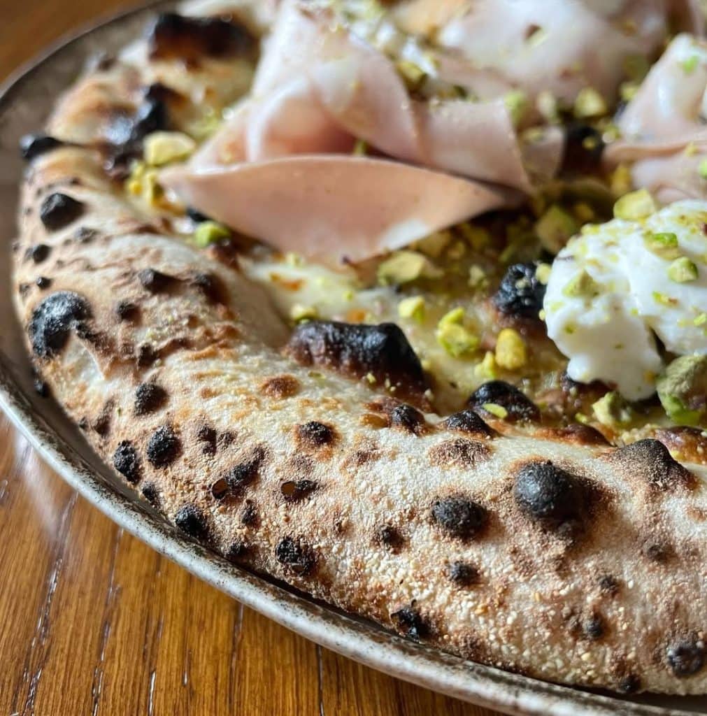 Homemade pizza with mortadella, ricotta, and pistachio. Baked in an Ooni outdoor pizza oven.