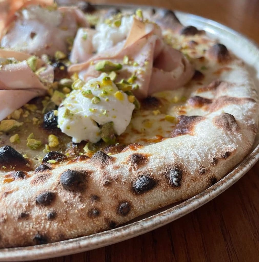 Homemade pizza with mortadella, ricotta, and pistachio. Baked in an Ooni outdoor pizza oven.