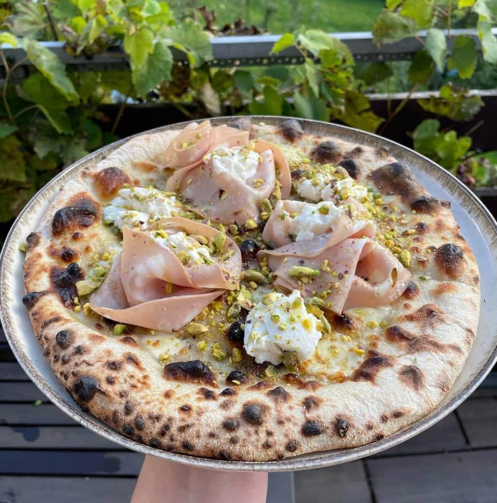 Homemade pizza with mortadella, ricotta, and pistachio. Baked in an Ooni outdoor pizza oven.