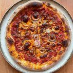 New York Style Margherita Pizza with red onion baked on baking steel.