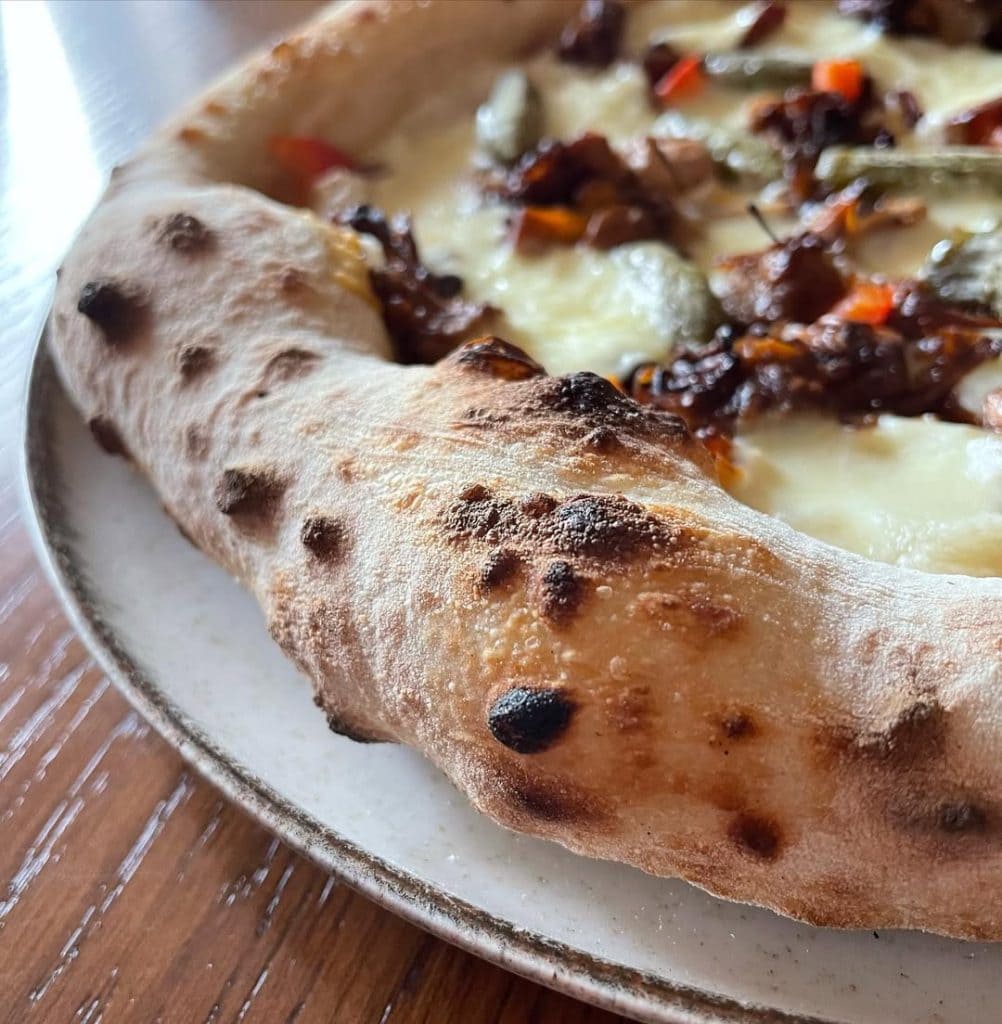 Homemade Neapolitan style pizza with jackfruit and pickles. Baked in an Ooni outdoor pizza oven
