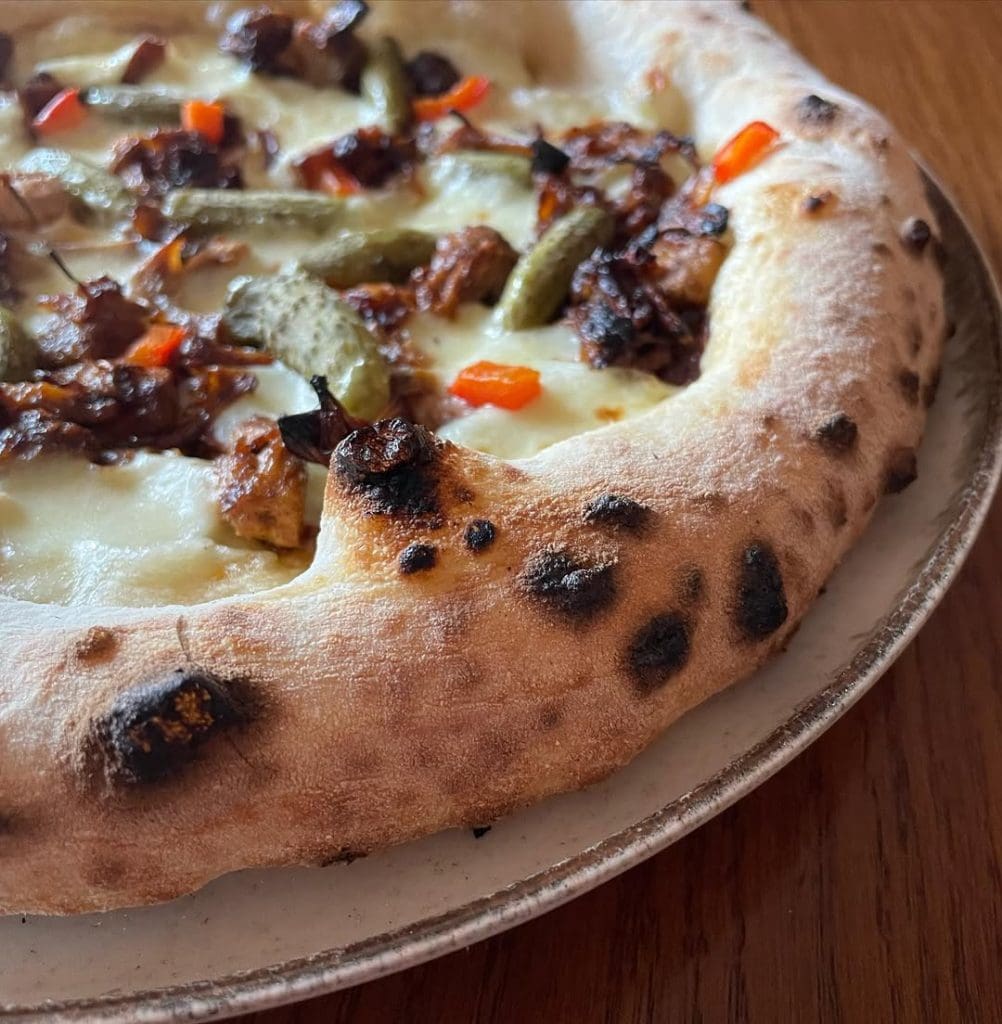 Homemade Neapolitan style pizza with jackfruit and pickles. Baked in an Ooni outdoor pizza oven