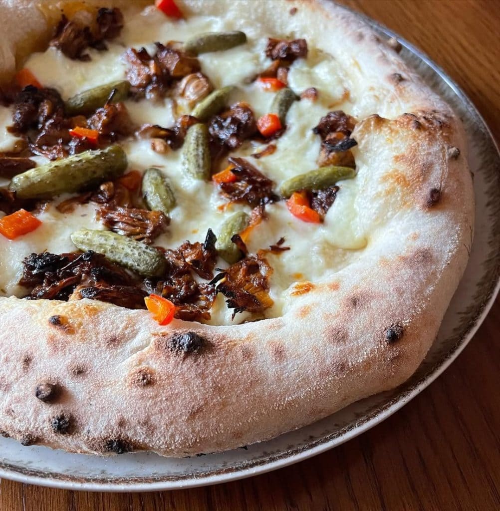 Homemade Neapolitan style pizza with jackfruit and pickles. Baked in an Ooni outdoor pizza oven