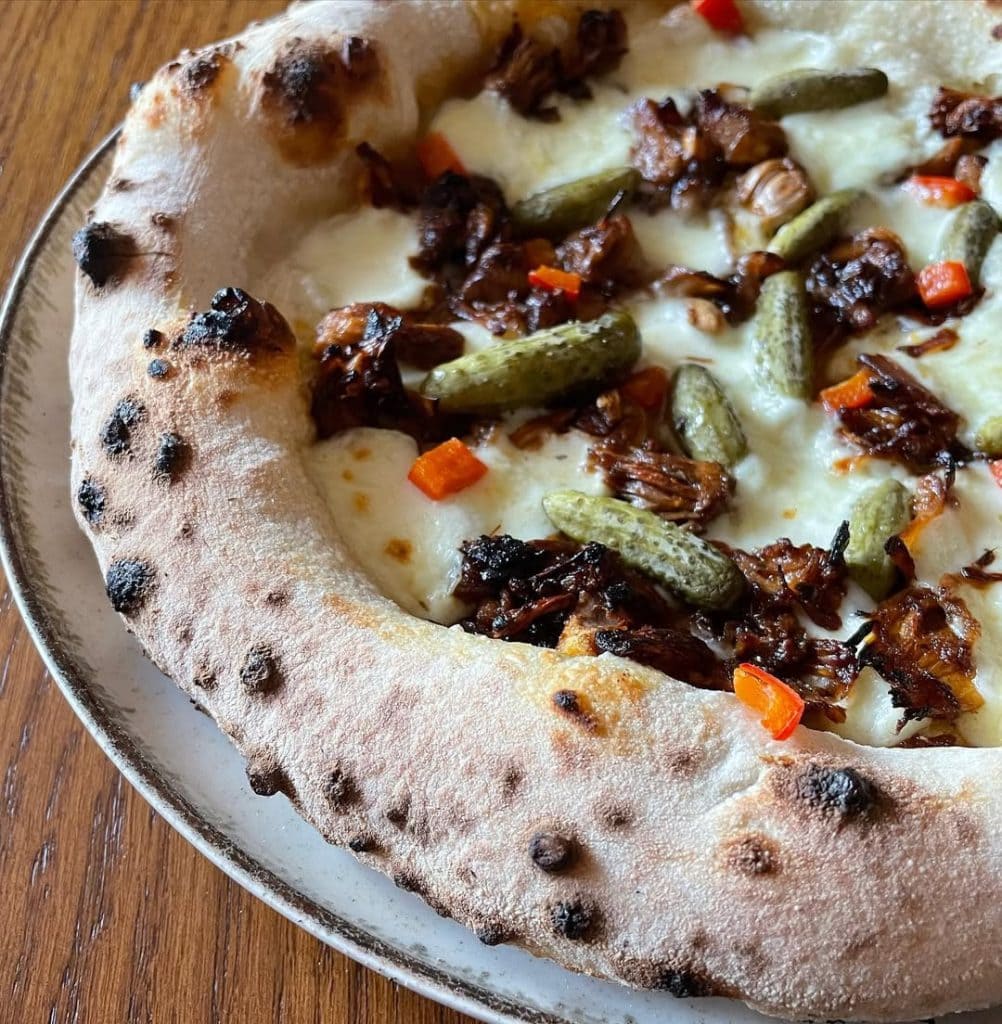 Homemade Neapolitan style pizza with jackfruit and pickles. Baked in an Ooni outdoor pizza oven