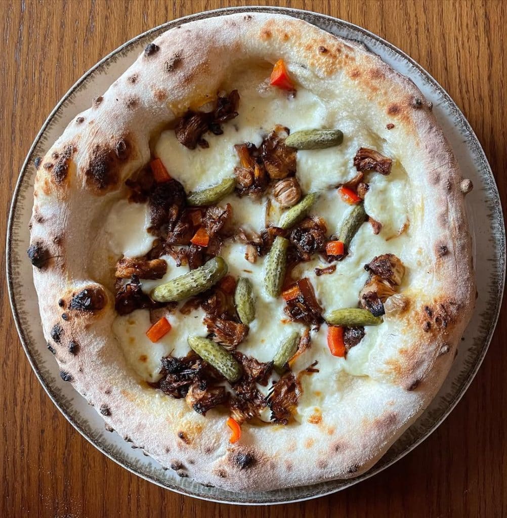Homemade Neapolitan style pizza with jackfruit and pickles. Baked in an Ooni outdoor pizza oven