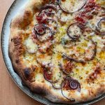 Homemade red onion and mozzarella pizza baked on a pizza steel in a home oven, topped with tomato sauce, melted mozzarella, red onion slices, oregano, and a drizzle of extra virgin olive oil.