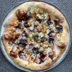 Polish-inspired homemade pizza topped with smoked oscypek cheese, crispy boczek bacon, and cranberry jam on a golden crust, finished with dried parsley and extra virgin olive oil. Baked in a home oven on baking steel.