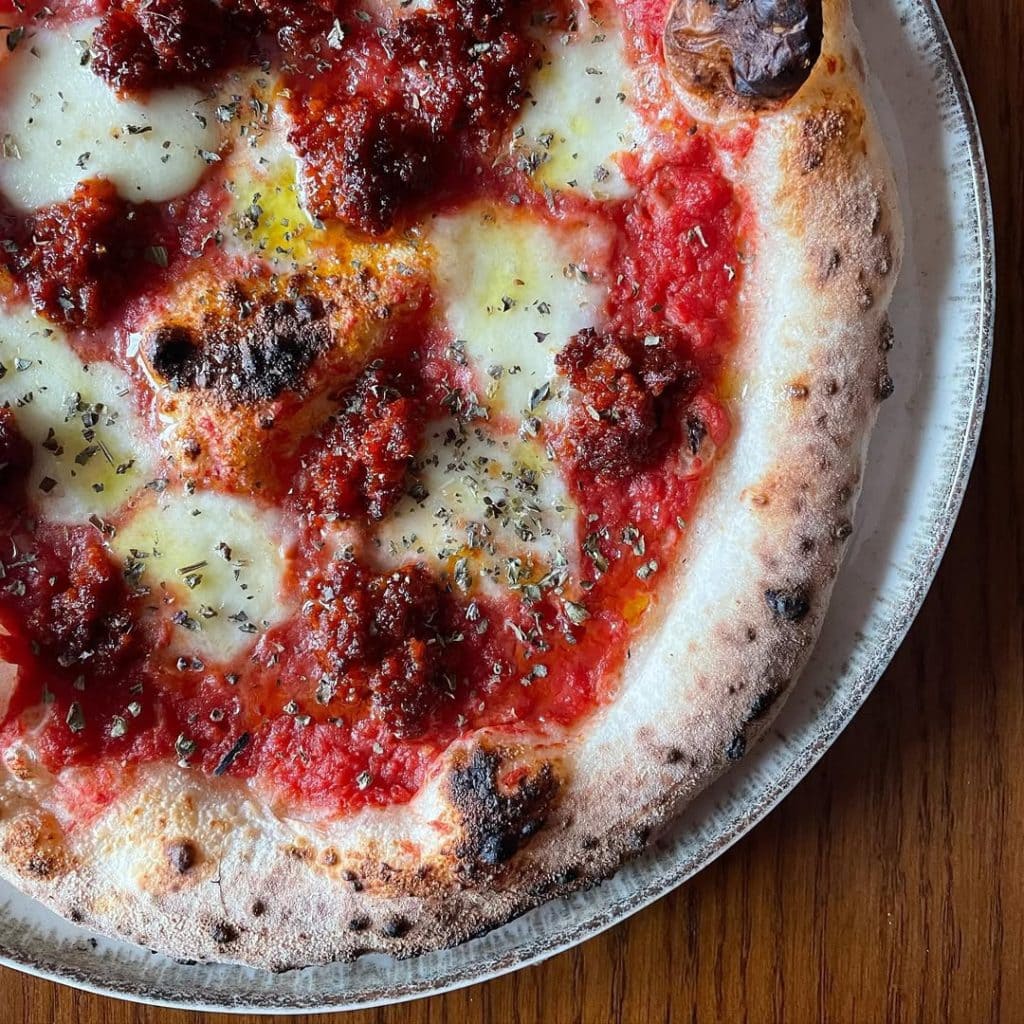 Neapolitan-style Nduja pizza topped with mozzarella fior di latte, rich tomato sauce, and spicy Calabrian nduja, finished with oregano and EVOO