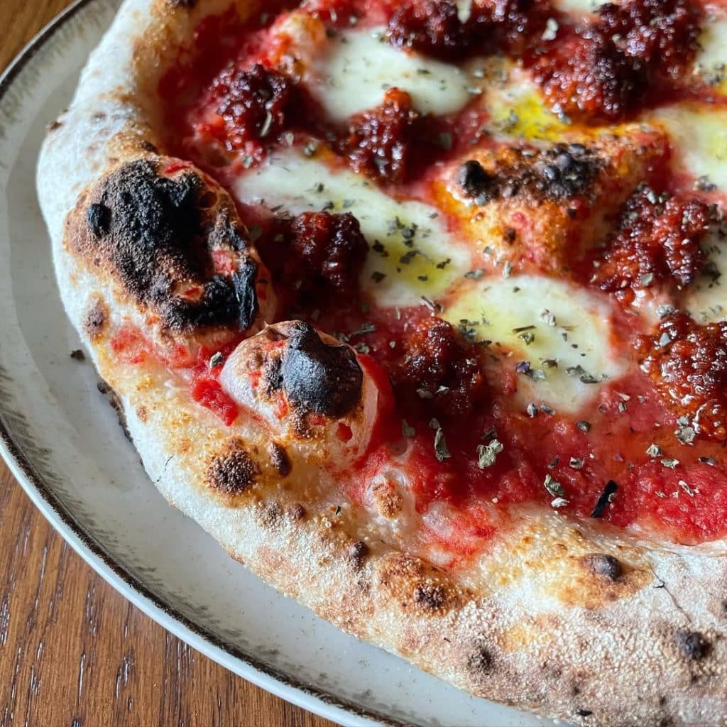 Neapolitan-style Nduja pizza topped with mozzarella fior di latte, rich tomato sauce, and spicy Calabrian nduja, finished with oregano and EVOO
