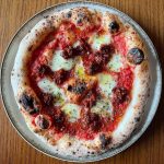Neapolitan-style Nduja pizza topped with mozzarella fior di latte, rich tomato sauce, and spicy Calabrian nduja, finished with oregano and EVOO