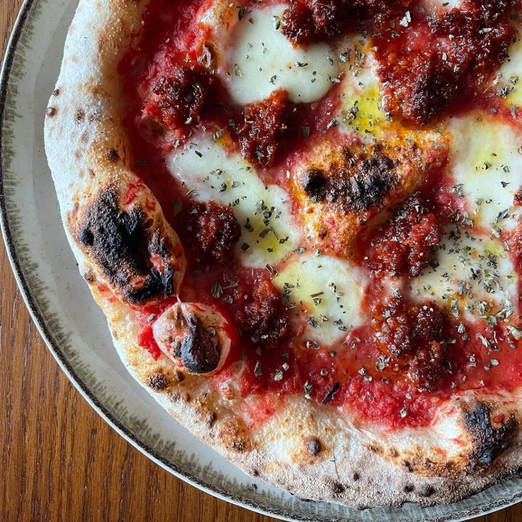 Neapolitan-style Nduja pizza topped with mozzarella fior di latte, rich tomato sauce, and spicy Calabrian nduja, finished with oregano and EVOO