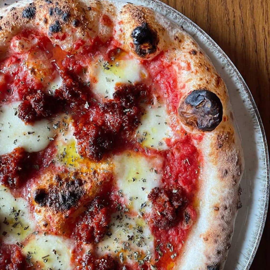 Neapolitan-style Nduja pizza topped with mozzarella fior di latte, rich tomato sauce, and spicy Calabrian nduja, finished with oregano and EVOO