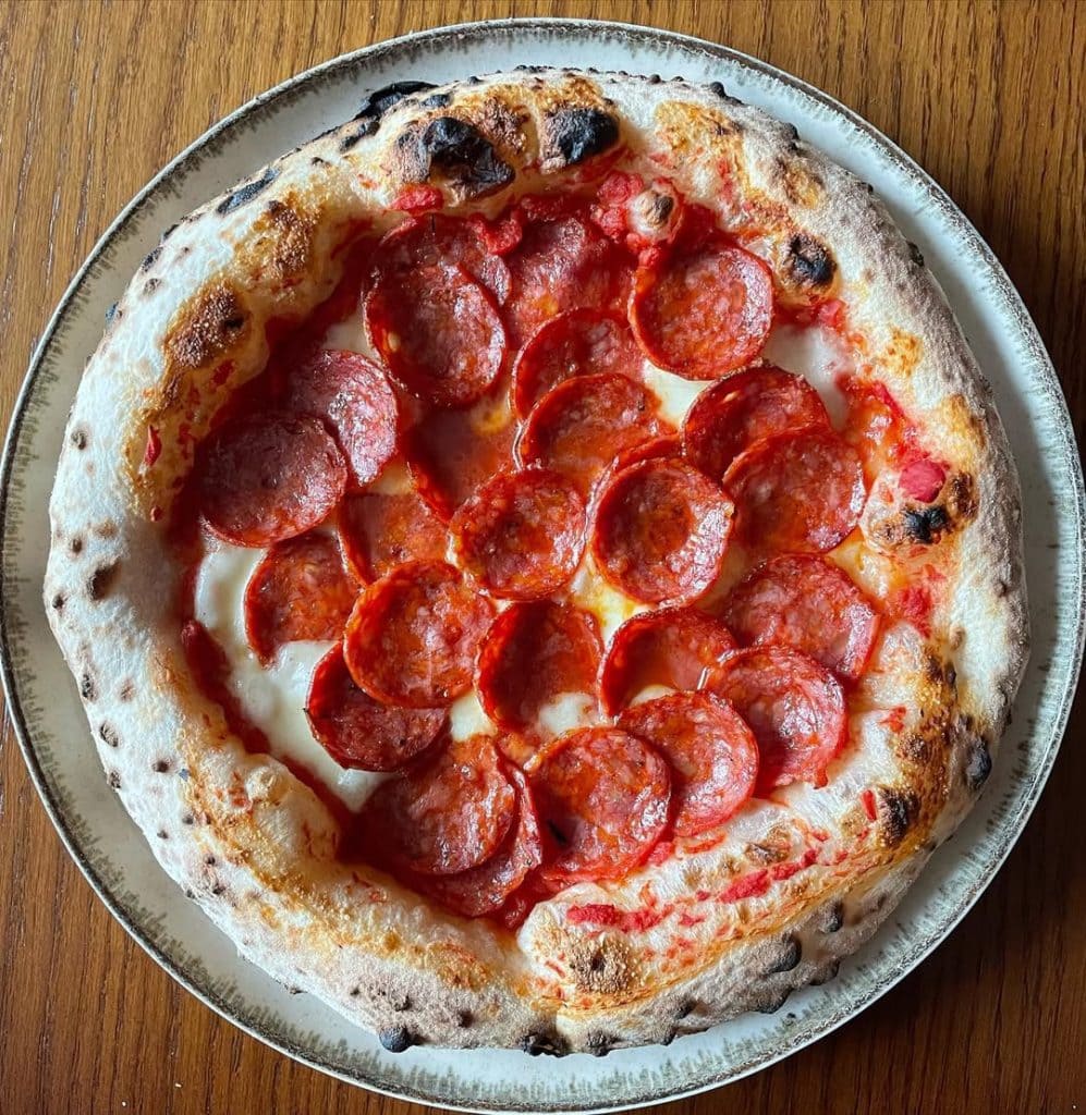 Neapolitan-style spicy pepperoni pizza topped with fior di latte mozzarella and tomato sauce, baked to a golden crust with crisp, curled pepperoni slices.