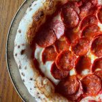 Neapolitan-style spicy pepperoni pizza topped with fior di latte mozzarella and tomato sauce, baked to a golden crust with crisp, curled pepperoni slices.