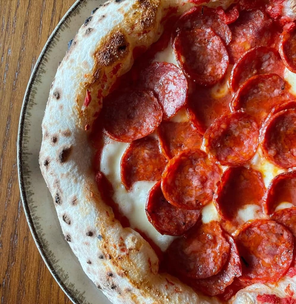 Neapolitan-style spicy pepperoni pizza topped with fior di latte mozzarella and tomato sauce, baked to a golden crust with crisp, curled pepperoni slices.