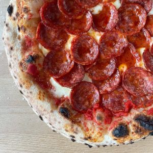 Neapolitan-style spicy pepperoni pizza topped with fior di latte mozzarella and tomato sauce, baked to a golden crust with crisp, curled pepperoni slices.