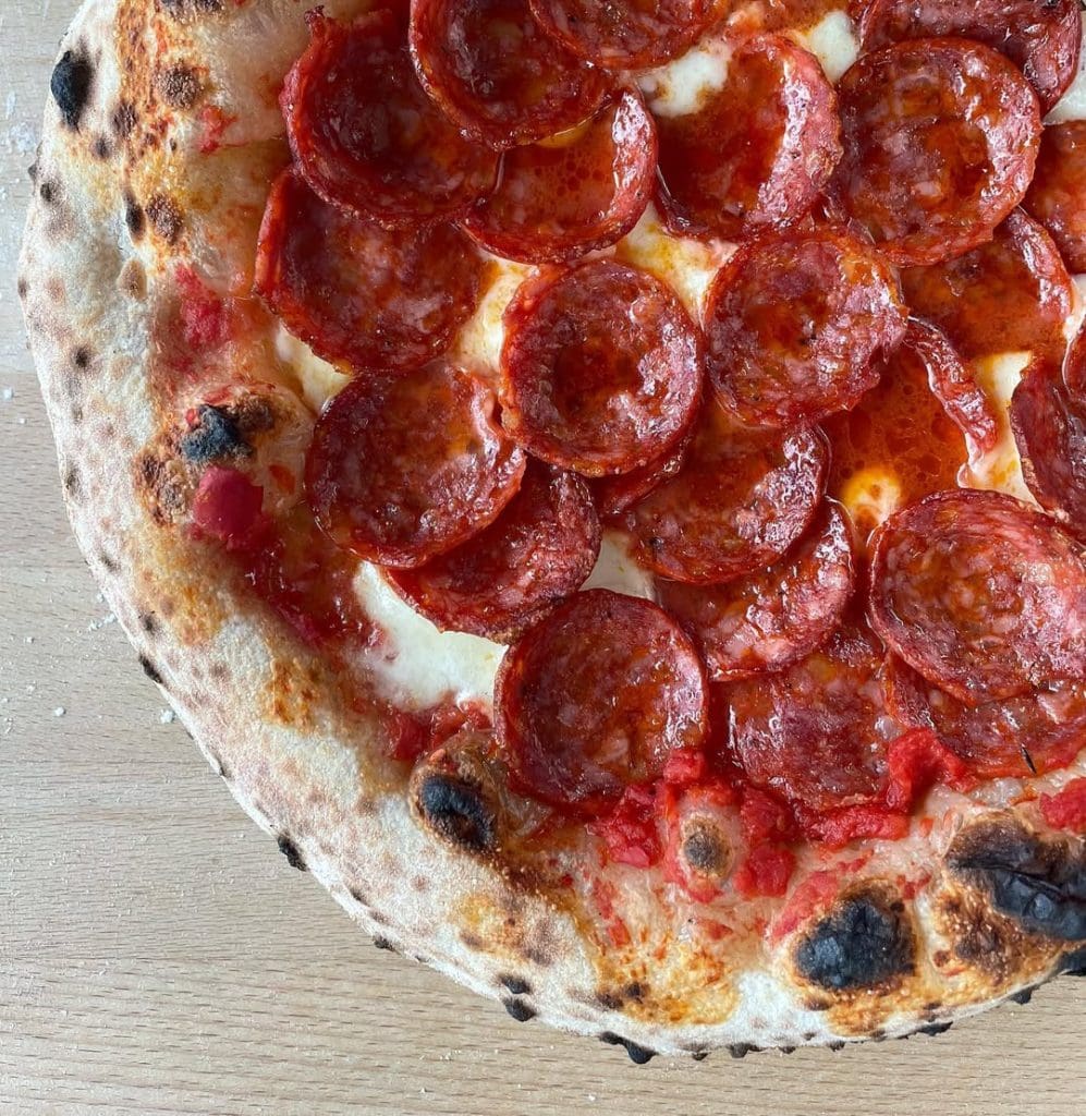 Neapolitan-style spicy pepperoni pizza topped with fior di latte mozzarella and tomato sauce, baked to a golden crust with crisp, curled pepperoni slices.