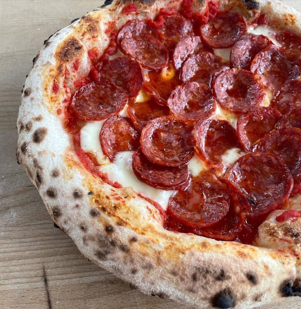 Neapolitan-style spicy pepperoni pizza topped with fior di latte mozzarella and tomato sauce, baked to a golden crust with crisp, curled pepperoni slices.